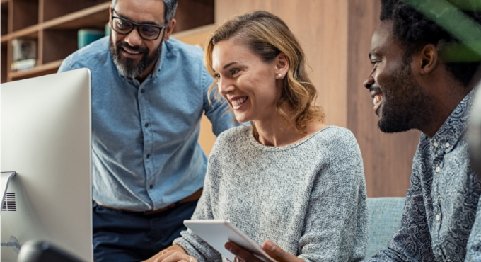 Three people looking at a computer smiling.