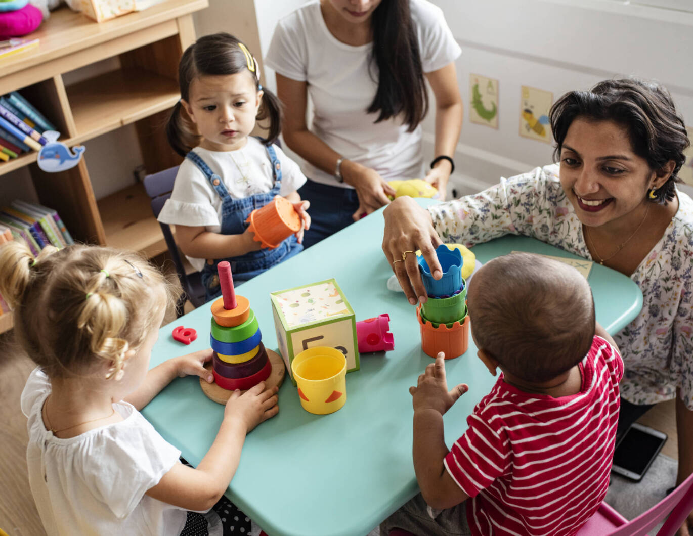 Nursery children playing with teacher in the classroom