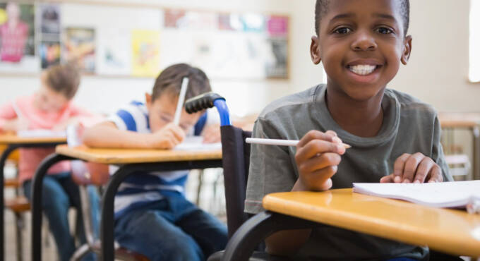 Boy in a wheelchair smiling in a classroom