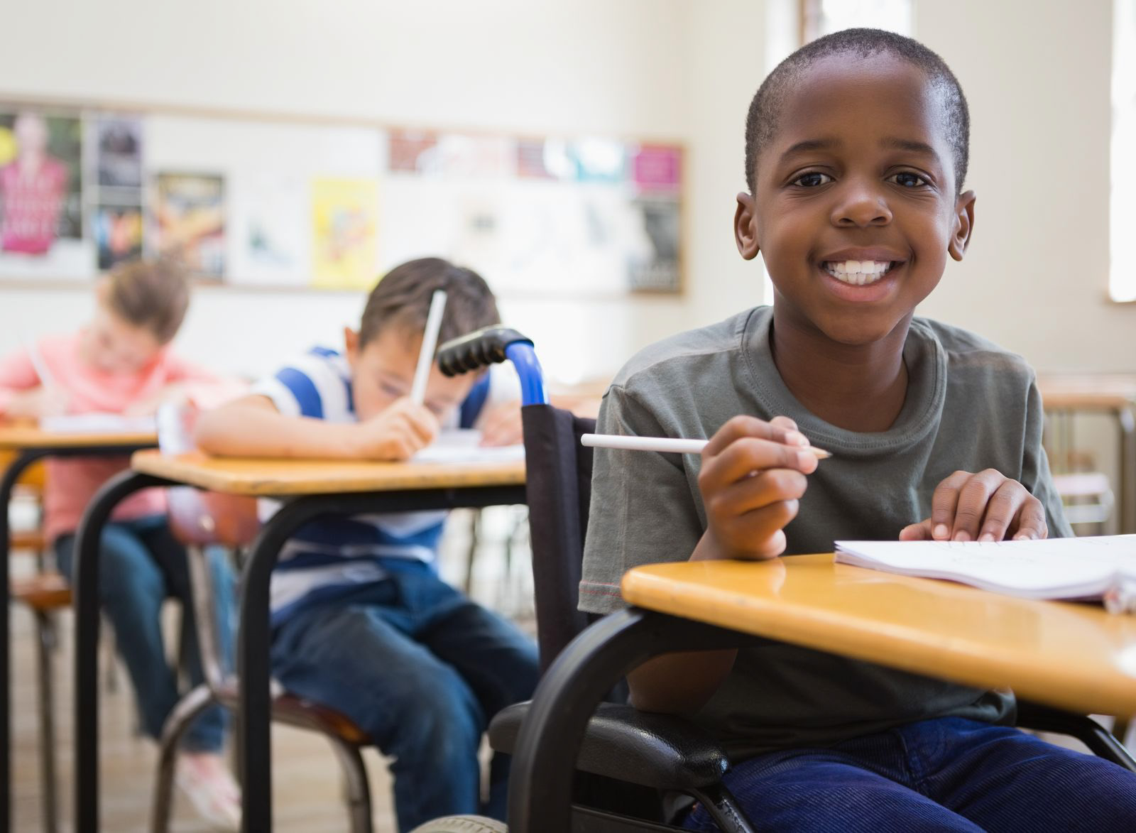 Boy in a wheelchair smiling in a classroom