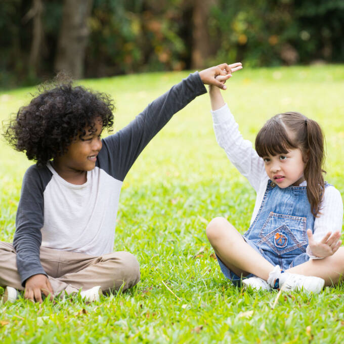 two kids sitting next to each other in a grass field